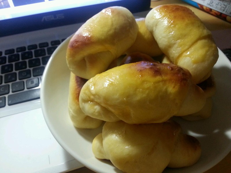 1. 将鸡蛋打撒,加入食盐,砂糖,牛奶混合,最后倒入水搅拌均匀待用(冬天使用热水时注意水温,切勿将蛋液烫熟)。在容器里放一半的强力小麦粉,倒入面包发酵粉搅匀,将之前做好的混合缓缓倒入并用手搅拌,最后倒入剩余的强力小麦粉和匀。待面团不是很粘手时,将其取出放在塑料砧板上加上牛油继续揉捻约15分钟,使原料充分混合。